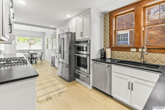 kitchen with stainless steel appliances, dark countertops, a sink, and a warming drawer