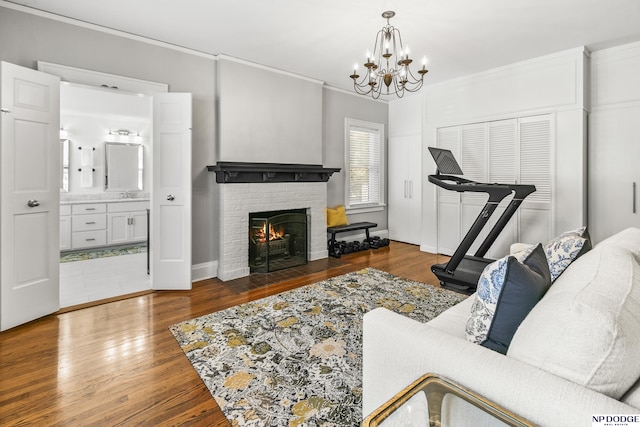living area with ornamental molding, wood finished floors, a notable chandelier, and a fireplace