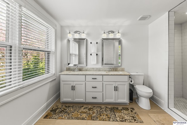 bathroom with a sink, toilet, wood finished floors, and a wealth of natural light
