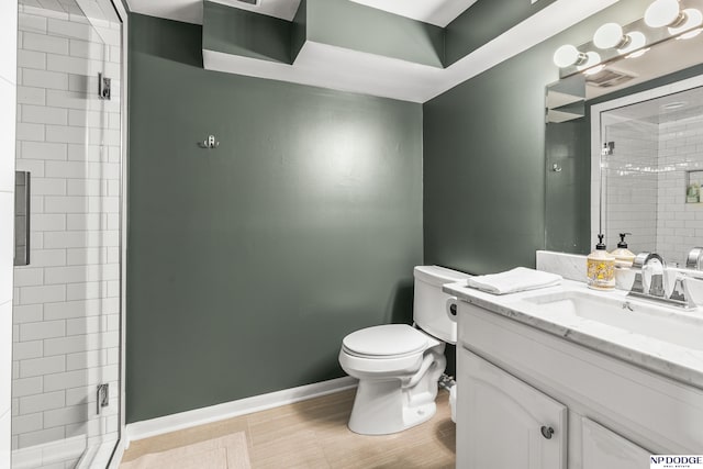 bathroom with baseboards, a stall shower, toilet, and vanity