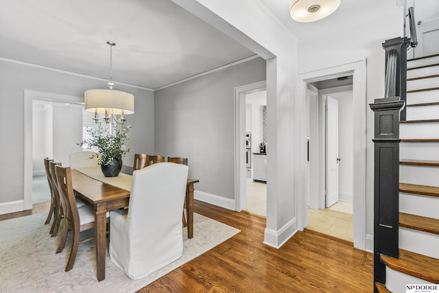 dining space featuring stairway, baseboards, wood finished floors, and a notable chandelier