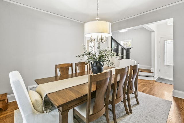 dining area featuring baseboards, ornamental molding, stairs, and wood finished floors