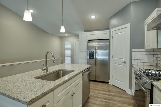 kitchen with decorative backsplash, pendant lighting, a sink, white cabinets, and stainless steel appliances