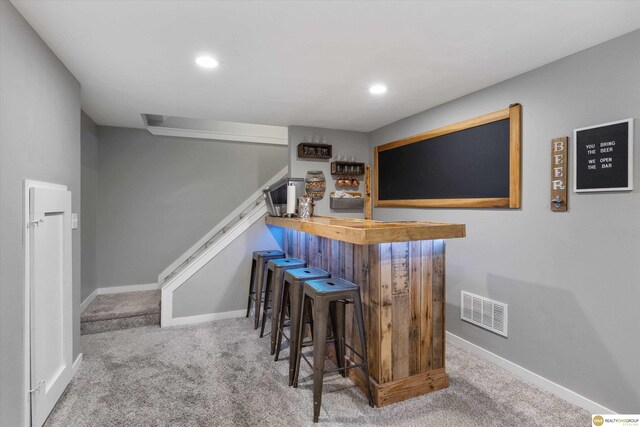 bar featuring stairs, visible vents, a dry bar, and carpet floors