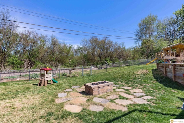 view of yard with a playground, a fenced backyard, and a fire pit