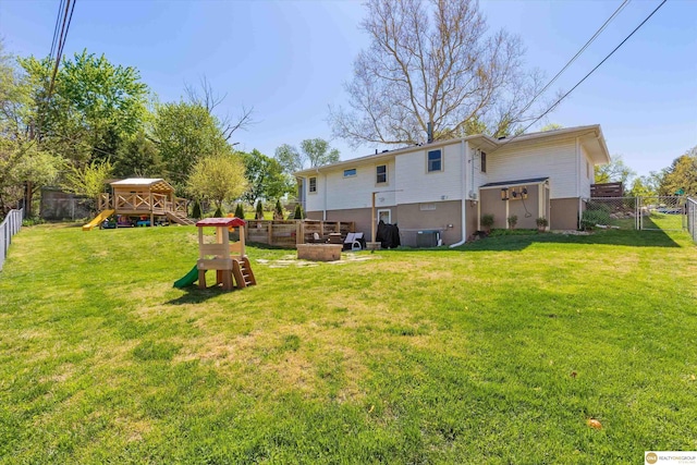 back of house with a playground, a yard, and a fenced backyard
