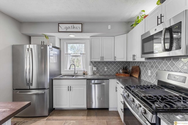 kitchen with white cabinets, stainless steel appliances, a sink, and tasteful backsplash