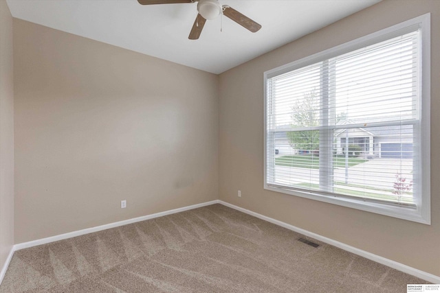 carpeted empty room featuring visible vents, a ceiling fan, baseboards, and plenty of natural light