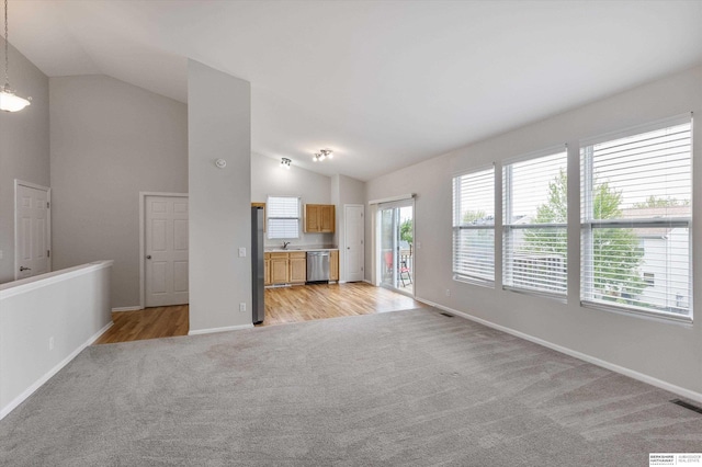 unfurnished living room featuring baseboards, vaulted ceiling, light carpet, and visible vents