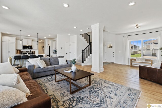 living area featuring recessed lighting, light wood-style floors, and stairs