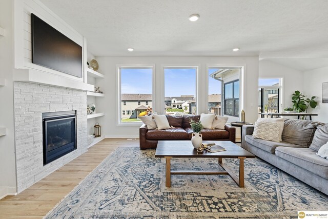 living room featuring recessed lighting, baseboards, a fireplace, and light wood-type flooring