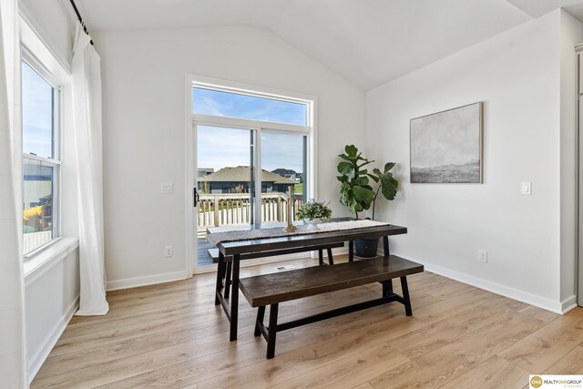 dining space featuring light wood-type flooring, baseboards, and lofted ceiling
