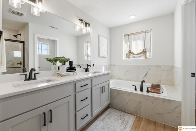 full bathroom featuring a sink, double vanity, a shower stall, visible vents, and a bath