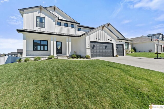 modern farmhouse style home featuring board and batten siding, fence, a front yard, and a garage