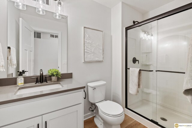 full bath featuring visible vents, vanity, wood finished floors, toilet, and a stall shower