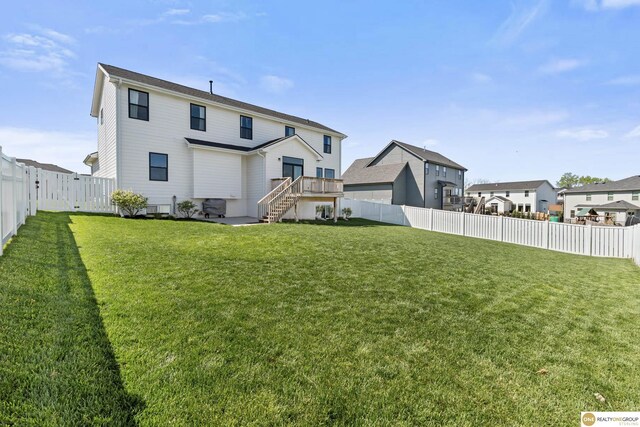rear view of house featuring a yard, a fenced backyard, and stairs