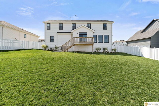 rear view of house with stairs, a fenced backyard, and a yard