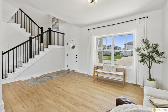 entryway featuring baseboards, stairs, and wood finished floors