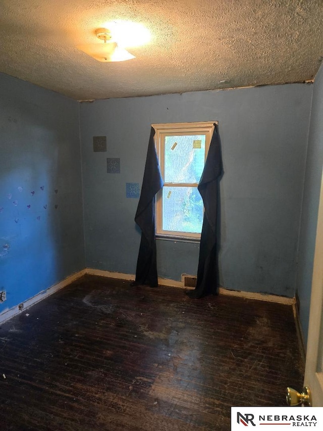 unfurnished room featuring hardwood / wood-style floors, a textured ceiling, and baseboards