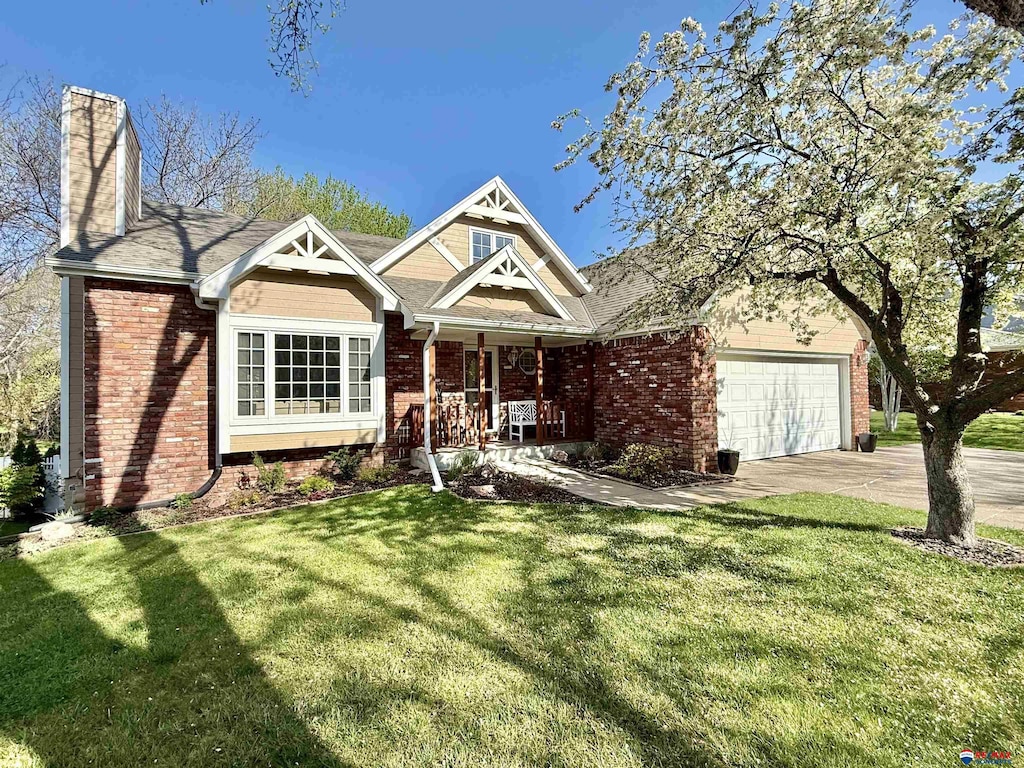 craftsman-style house featuring a porch, brick siding, a chimney, and a front yard