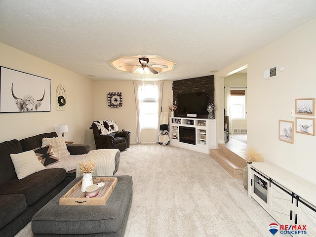 living room featuring a fireplace, ceiling fan, light carpet, and visible vents