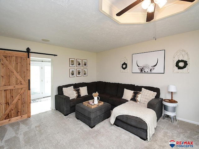 carpeted living room featuring a ceiling fan, a textured ceiling, and a barn door