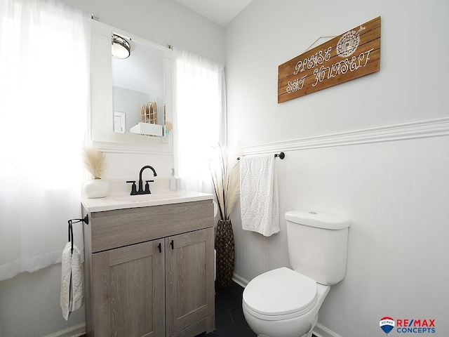 half bath with vanity, baseboards, and toilet