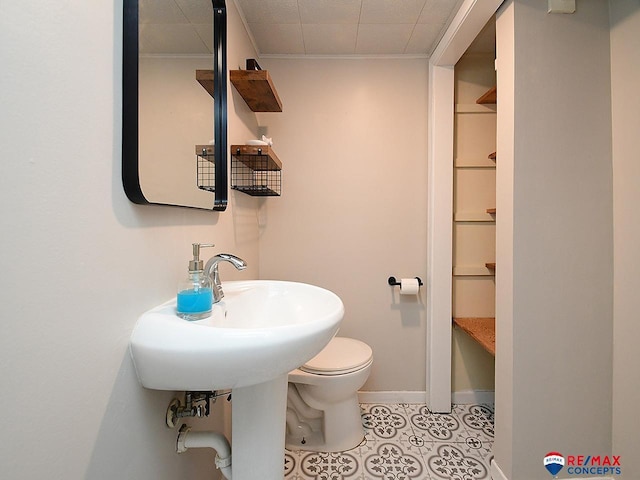 bathroom featuring crown molding, baseboards, and toilet