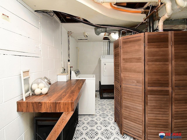 laundry room featuring washing machine and clothes dryer and concrete block wall