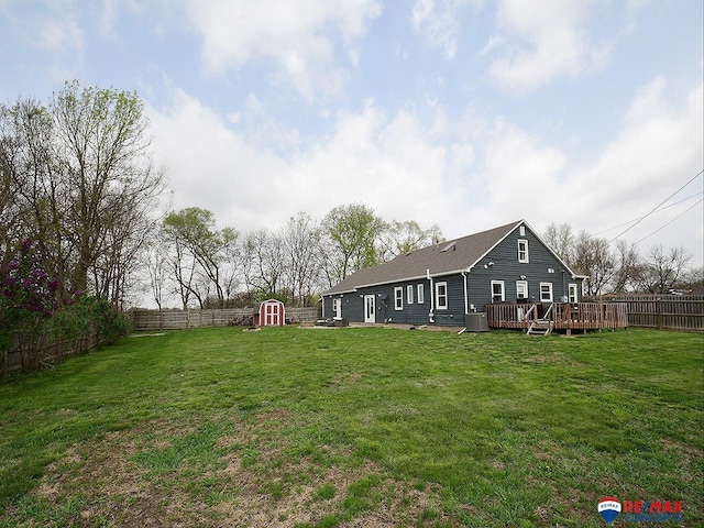 view of yard featuring a deck, a shed, a fenced backyard, an outbuilding, and central AC unit
