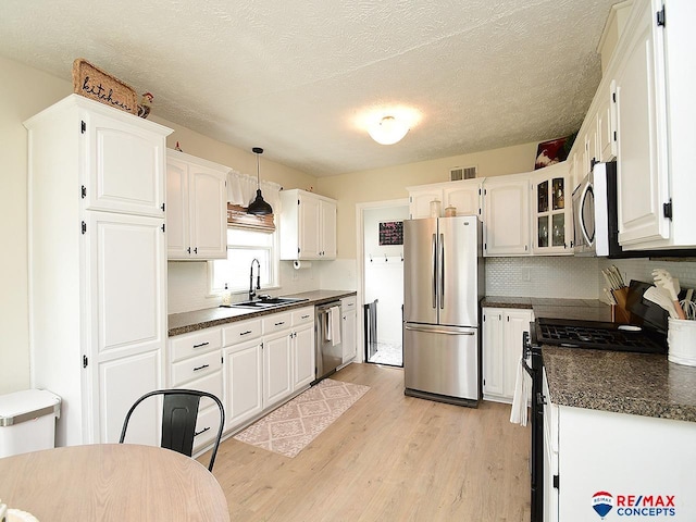 kitchen featuring visible vents, dark countertops, light wood-type flooring, a sink, and stainless steel appliances