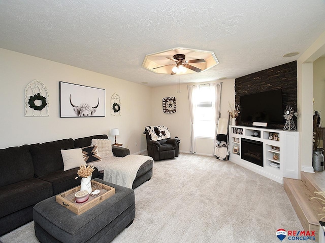 carpeted living room featuring a textured ceiling, ceiling fan, and a fireplace