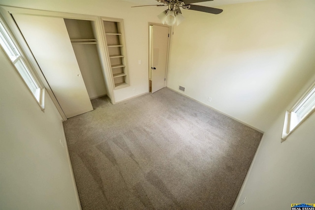 unfurnished bedroom featuring light colored carpet, a ceiling fan, visible vents, and a closet