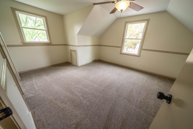 additional living space with visible vents, ceiling fan, light colored carpet, and vaulted ceiling