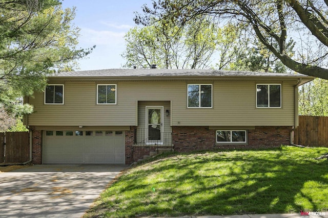 bi-level home with brick siding, fence, a front lawn, concrete driveway, and an attached garage