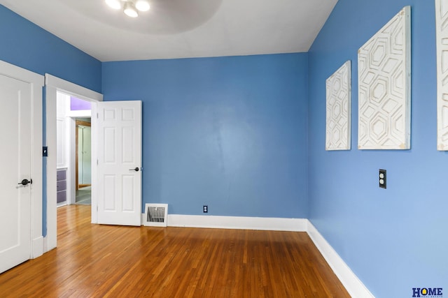 unfurnished bedroom with baseboards, wood finished floors, and visible vents