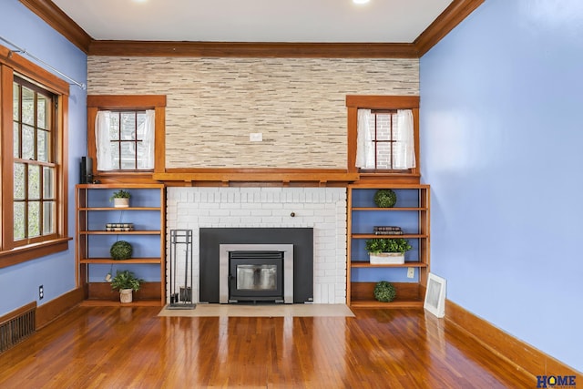 unfurnished living room featuring ornamental molding, a fireplace, wood finished floors, and visible vents