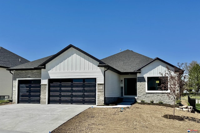 modern inspired farmhouse with a garage, stone siding, roof with shingles, board and batten siding, and concrete driveway