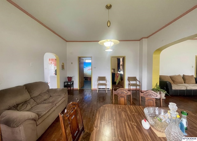 dining area with arched walkways, wood finished floors, and ornamental molding