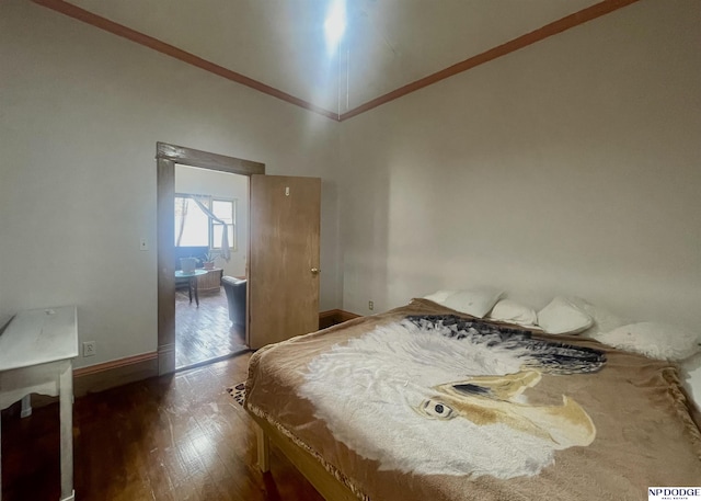 bedroom with crown molding, baseboards, and wood finished floors