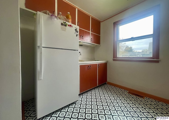 kitchen featuring light countertops, light floors, and freestanding refrigerator