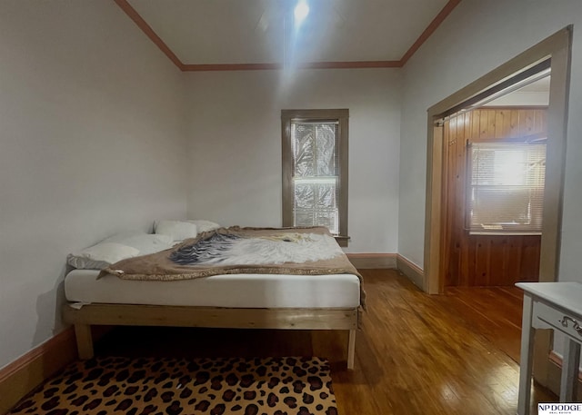 bedroom featuring baseboards, ornamental molding, and wood finished floors