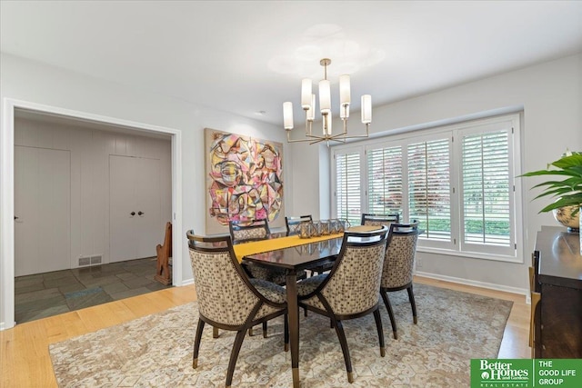 dining space with baseboards, visible vents, wood finished floors, and a notable chandelier