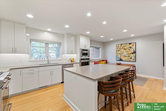 kitchen with a sink, white cabinetry, a wealth of natural light, and stainless steel appliances