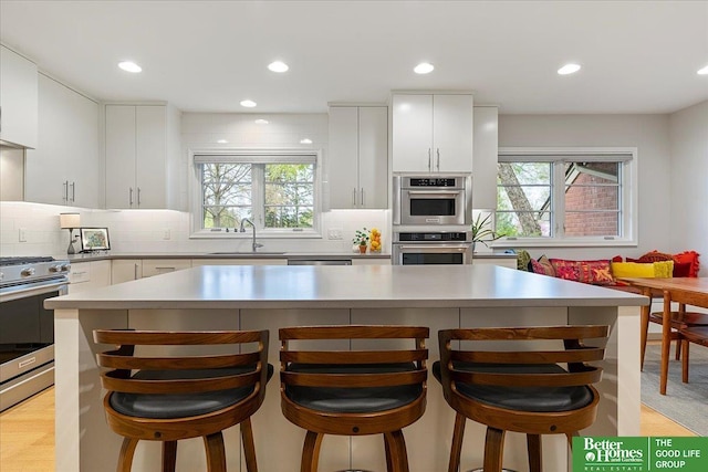 kitchen with a sink, appliances with stainless steel finishes, plenty of natural light, and decorative backsplash
