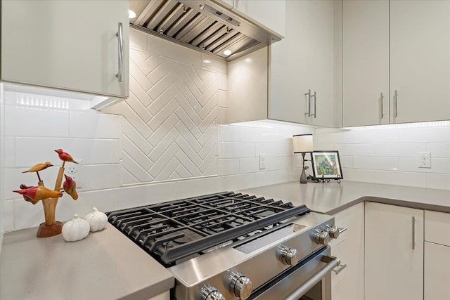kitchen with stainless steel range with gas cooktop, backsplash, white cabinets, and custom range hood