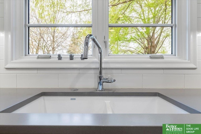 interior details featuring a sink, backsplash, and dark countertops