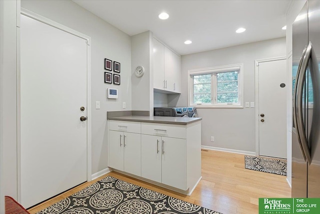 kitchen with light wood-style floors, freestanding refrigerator, white cabinetry, and a peninsula