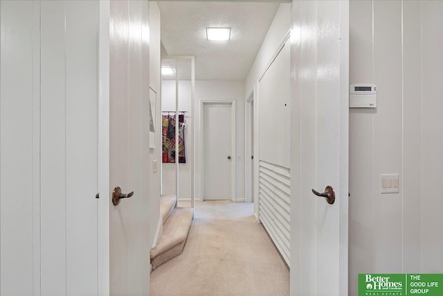 corridor with light carpet and a textured ceiling