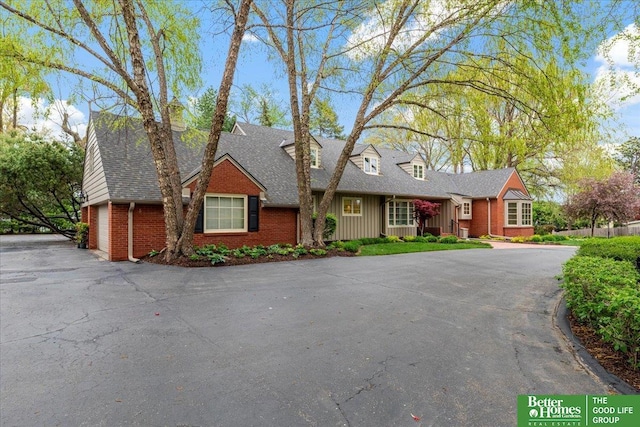 view of front of property featuring brick siding, aphalt driveway, and roof with shingles